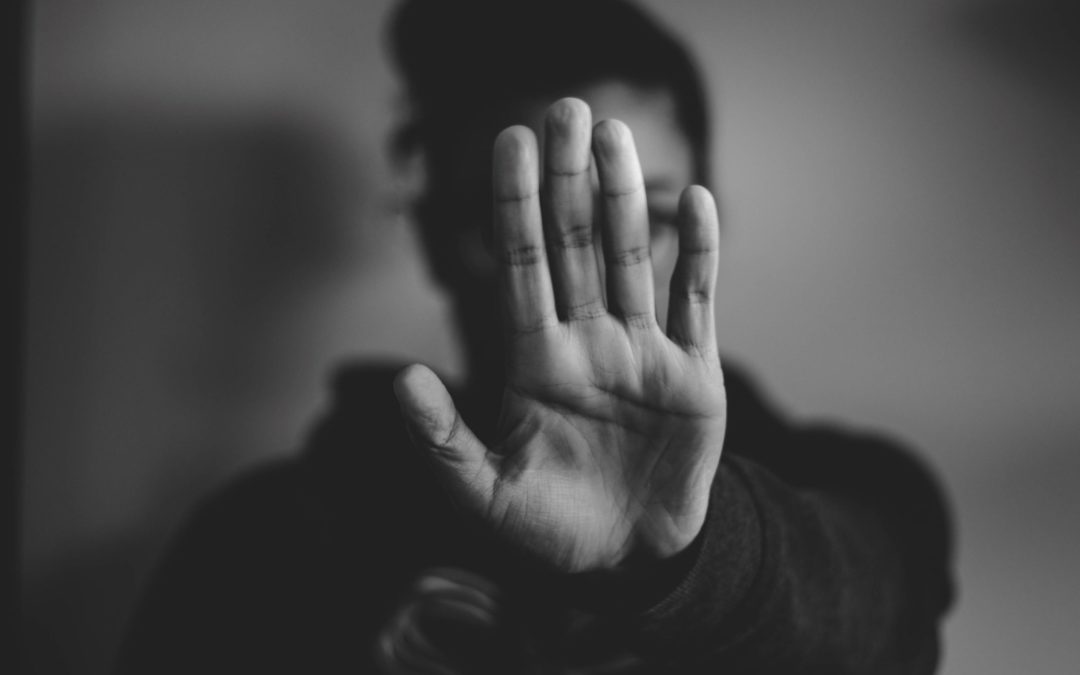 woman holding up her hand in front of her face implying "stop"